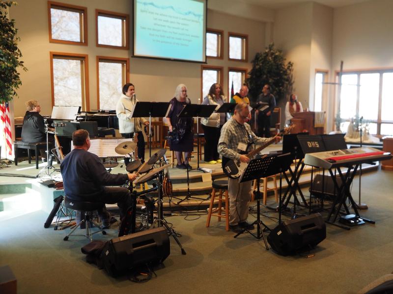A seven-piece contemporary praise band playing in a church worship sanctuary.